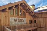 Experience the charm of this rustic wooden chalet, featuring a stone facade with the 'Le Bois Des Ours' inscription.