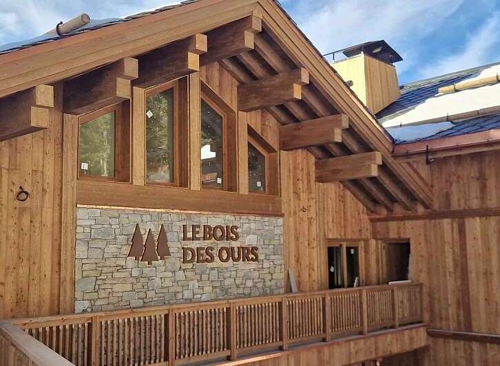 Experience the rustic charm of this timber-framed building, featuring a stone facade with the prominent 'LEBOIS DES OURS' signage.