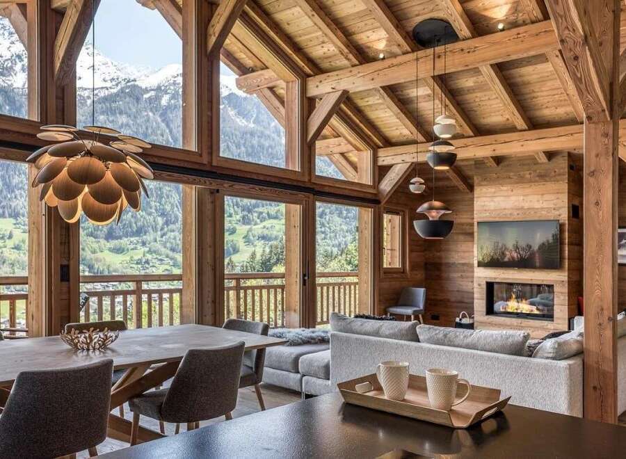 Experience luxury mountain living in this stunning chalet, featuring a grand open-plan living area with a cozy fireplace and breathtaking panoramic views of the snow-capped peaks.