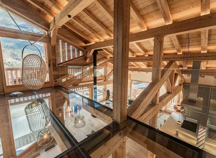Experience luxury mountain living in this stunning chalet featuring a unique glass floor and exposed wooden beams.
