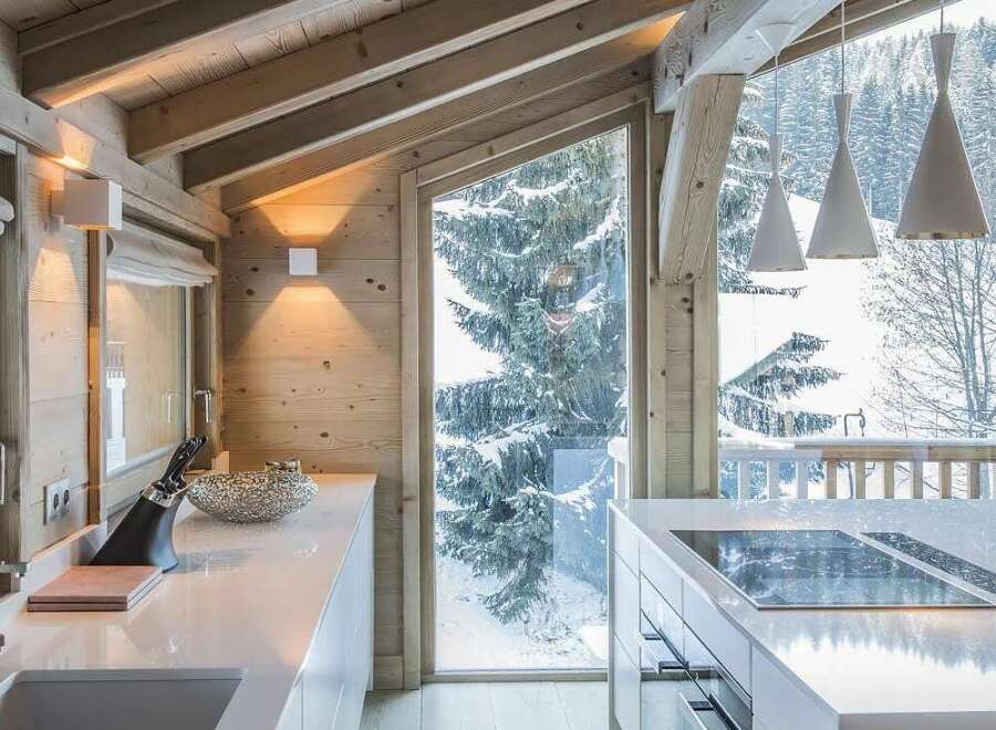 Experience luxury mountain living in this stunning modern kitchen, featuring sleek white countertops and a central island with a built-in stovetop.