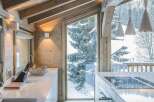 Experience luxury mountain living in this stunning modern kitchen, featuring sleek white countertops and a central island with a built-in stovetop.