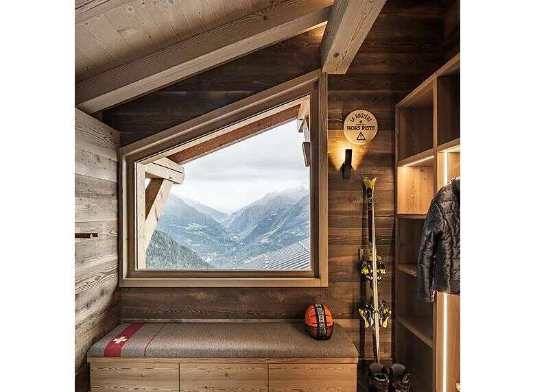 Experience breathtaking mountain views from this charming ski chalet, featuring a cozy built-in bench with storage and a rustic wooden interior.