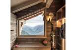 Experience breathtaking mountain views from this charming ski chalet, featuring a cozy built-in bench with storage and a rustic wooden interior.