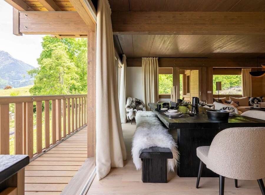 Experience luxurious mountain living in this stunning dining area, featuring a rustic wooden table set for a feast and plush, fur-covered seating.