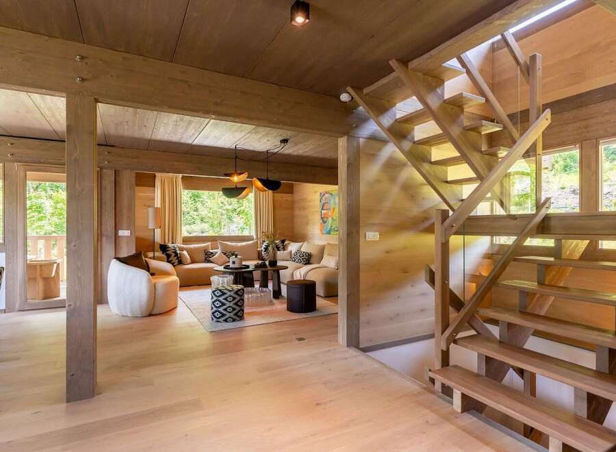 Experience luxurious mountain living in this stunning wooden chalet, featuring a spacious open-plan living area with a comfortable sectional sofa and modern pendant lighting.