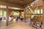 Experience luxurious mountain living in this stunning wooden chalet, featuring a spacious open-plan living area with a comfortable sectional sofa and modern pendant lighting.