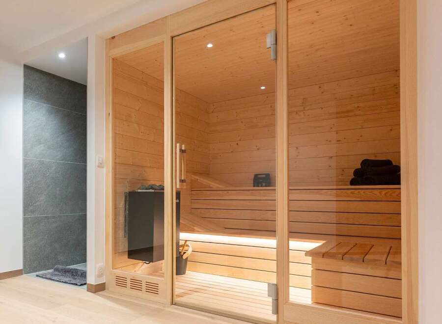 Experience ultimate relaxation in this modern home sauna, featuring a spacious interior with warm wood paneling and comfortable seating.