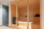 Experience ultimate relaxation in this modern home sauna, featuring a spacious interior with warm wood paneling and comfortable seating.