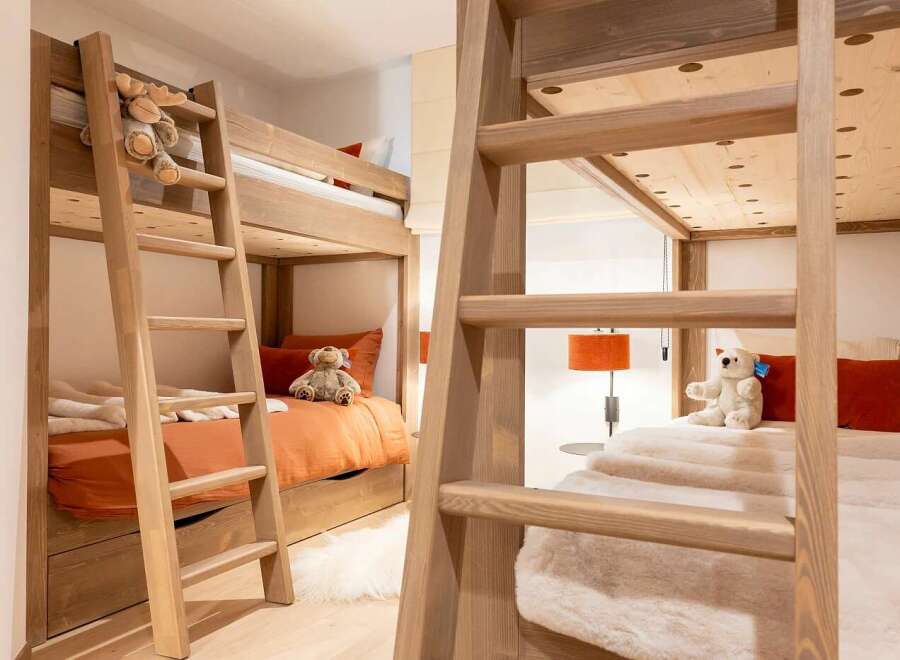 This charming children's bedroom features a pair of sturdy wooden bunk beds, perfect for sleepovers or accommodating multiple children.
