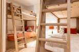This charming children's bedroom features a pair of sturdy wooden bunk beds, perfect for sleepovers or accommodating multiple children.