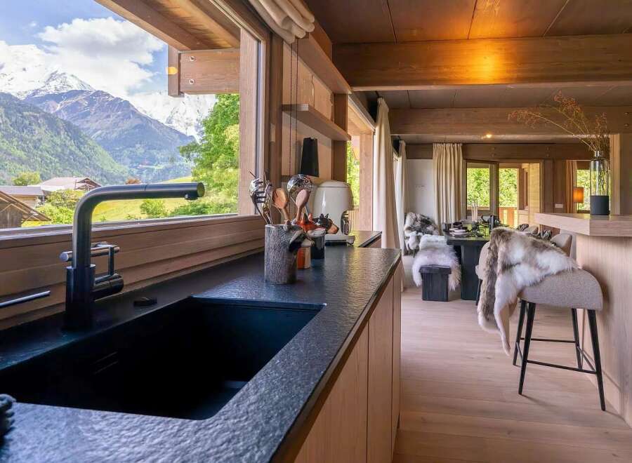 Experience the ultimate alpine retreat in this stunning kitchen, boasting a sleek black granite countertop and a modern faucet with a breathtaking mountain view.