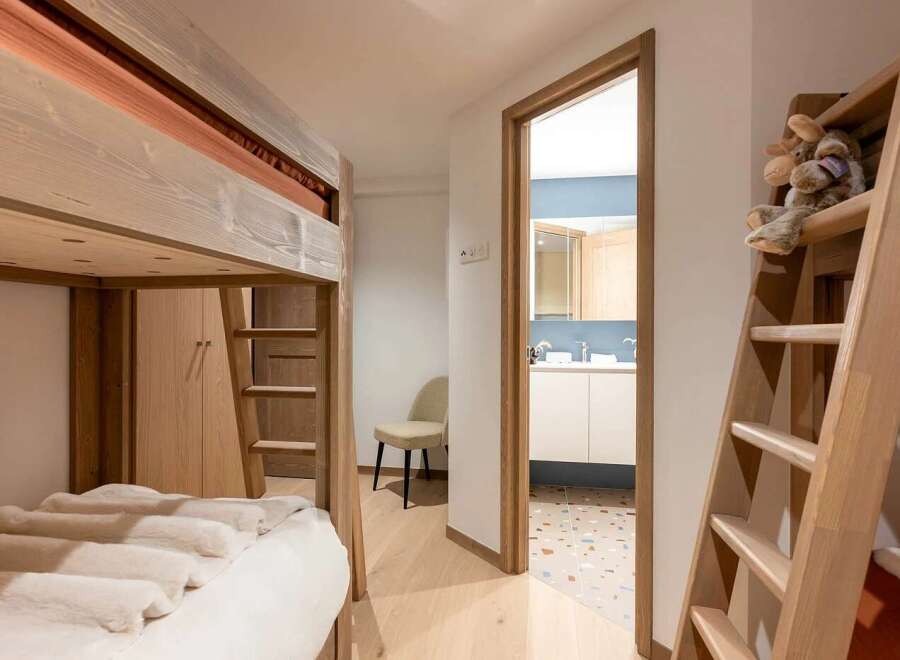 This charming bedroom features a space-saving bunk bed with a cozy, fur-covered lower bunk, perfect for children or guests.