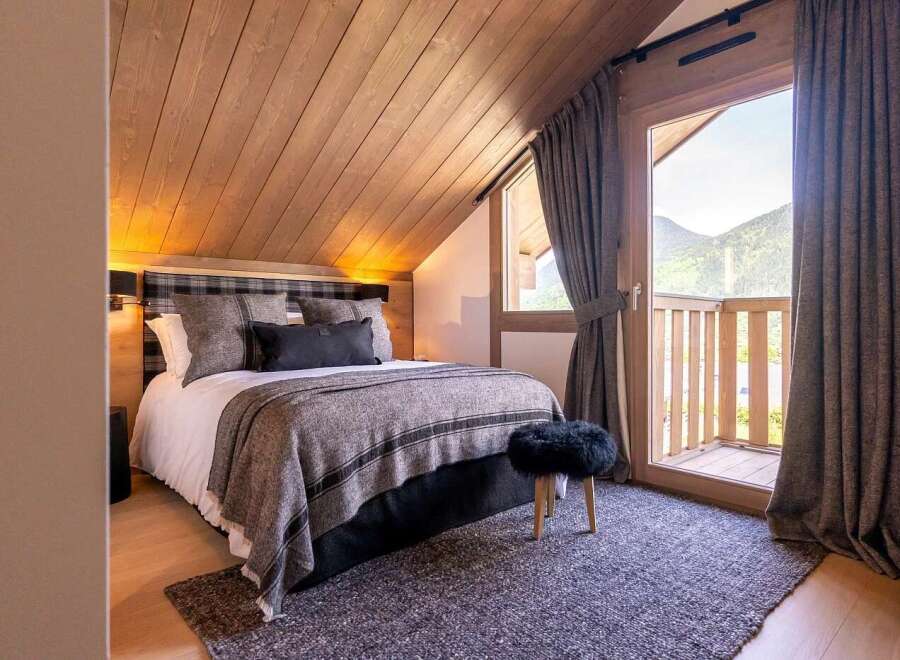 Experience ultimate comfort in this cozy bedroom, featuring a plush king-size bed adorned with luxurious grey linens and a plaid headboard.
