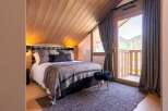 Experience ultimate comfort in this cozy bedroom, featuring a plush king-size bed adorned with luxurious grey linens and a plaid headboard.