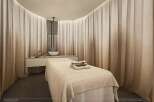 Experience ultimate relaxation in this serene massage room, featuring a comfortable treatment bed and a modern vanity area.