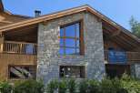 Experience luxury living in this stunning chalet, featuring a striking stone facade and expansive wooden beams.