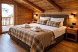 Experience rustic charm and modern comfort in this beautifully appointed bedroom, featuring warm wood paneling and a cozy plaid comforter.