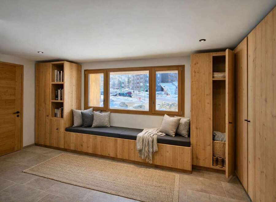 This modern entryway features a built-in wooden bench with a dark gray cushion, perfect for a cozy seating area.