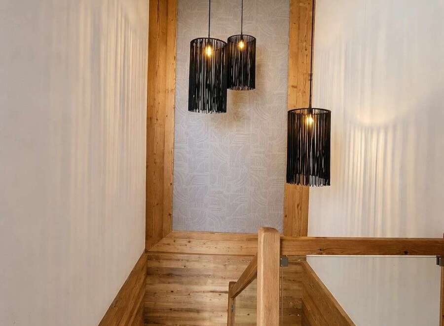 Ascend this stunning wooden staircase, bathed in the warm glow of unique black pendant lights.
