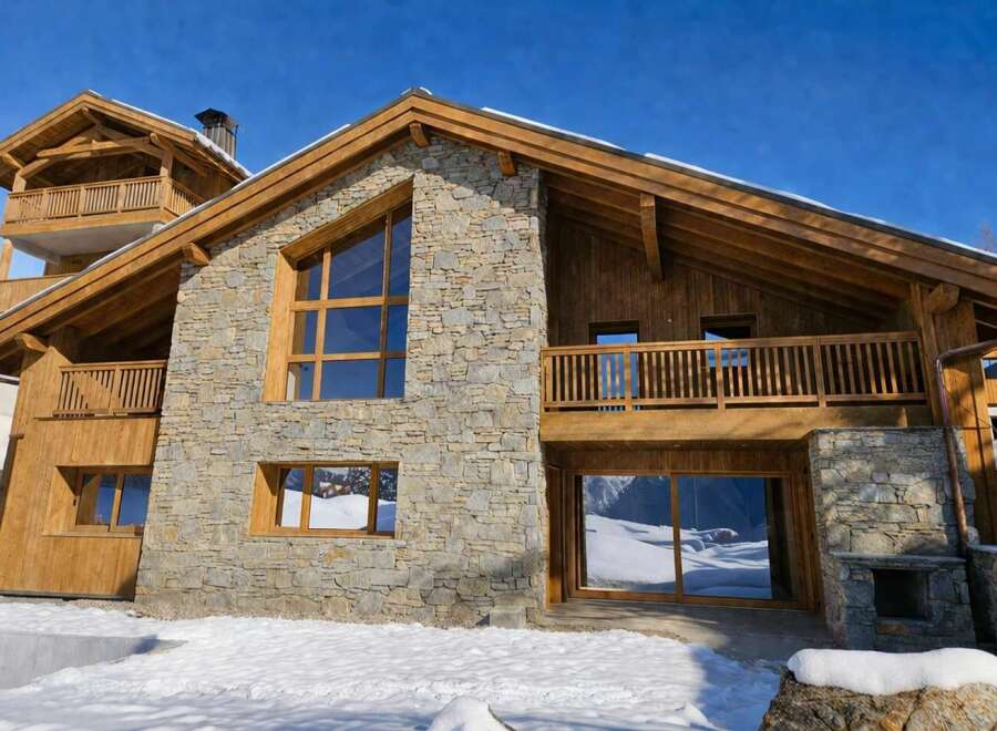 Experience luxury mountain living in this stunning chalet, featuring a striking stone and wood facade.