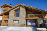 Experience luxury mountain living in this stunning chalet, featuring a striking stone and wood facade.