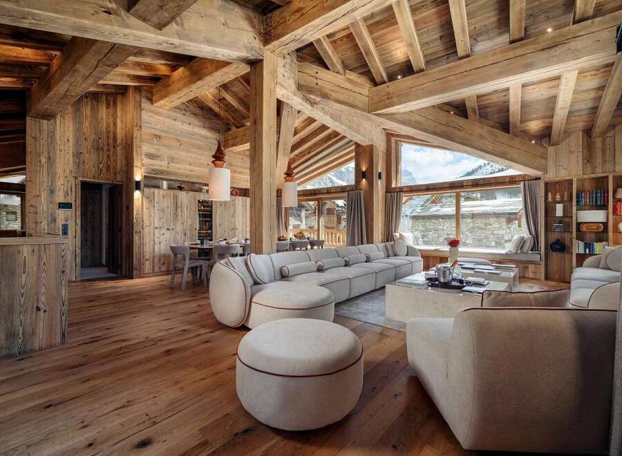 Experience luxury mountain living in this stunning chalet, featuring a spacious open-plan living area with exposed wooden beams and a grand fireplace.