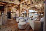 Experience luxury mountain living in this stunning chalet, featuring a spacious open-plan living area with exposed wooden beams and a grand fireplace.