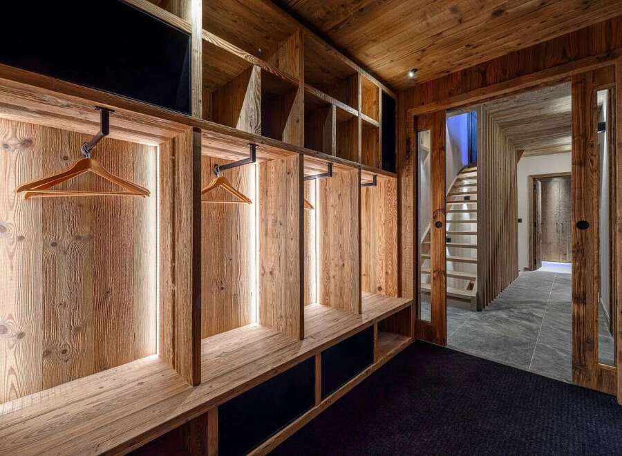 Experience rustic luxury in this mountain chalet featuring a bespoke wooden entryway with integrated benches and ample storage.