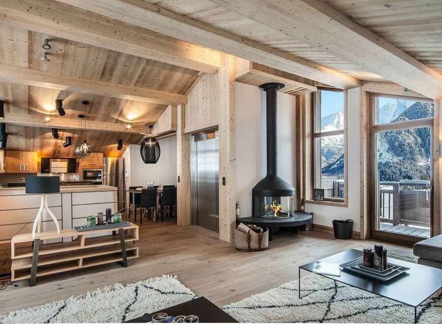 Experience luxury mountain living in this stunning chalet featuring a modern open-plan living space with a striking suspended fireplace and panoramic mountain views.