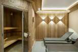 Experience ultimate relaxation in this luxurious spa area, featuring a traditional wooden sauna with glass doors and comfortable lounge chairs.