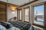 Experience luxury mountain living in this stunning bedroom featuring natural wood accents and exposed beams.