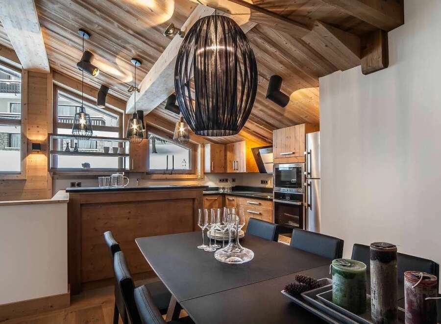 Experience luxurious mountain living in this stunning chalet, featuring a vaulted wood-paneled ceiling and a modern kitchen.