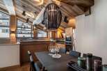 Experience luxurious mountain living in this stunning chalet, featuring a vaulted wood-paneled ceiling and a modern kitchen.