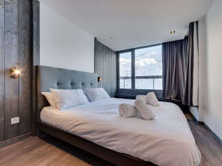 Experience ultimate comfort in this beautifully appointed bedroom, featuring a plush king-size bed with crisp white linens and a striking grey upholstered headboard.