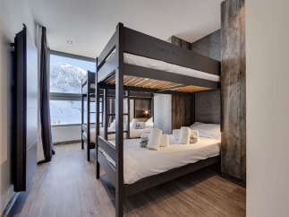 Experience ultimate comfort in this modern ski chalet bedroom, featuring multiple bunk beds perfect for families or groups.