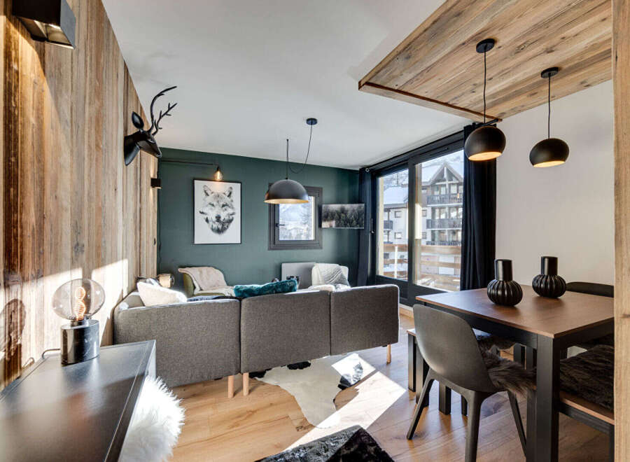 Experience cozy mountain living in this stylish apartment, featuring a modern living area with a plush sofa and a striking wolf artwork.