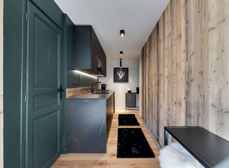 Experience modern alpine living in this stylish apartment, featuring a sleek, dark marble kitchen with integrated appliances and ambient lighting.