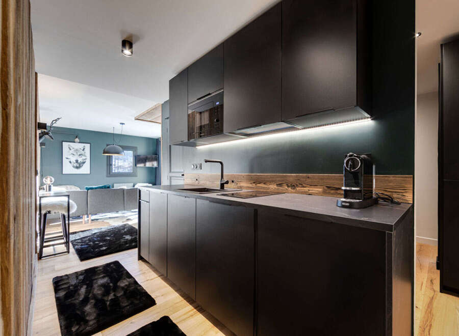 Experience modern living in this sleek kitchen featuring dark cabinetry and a striking wooden backsplash.