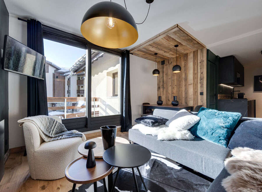 Experience modern alpine living in this stylish apartment, featuring a spacious living area with a large window offering scenic views.