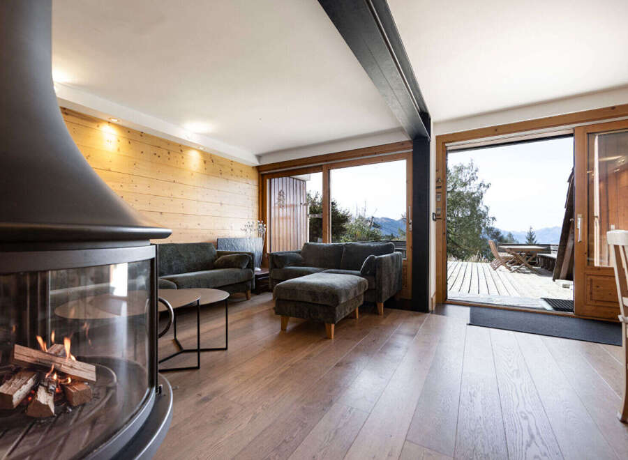 Experience cozy mountain living in this charming living room, featuring a modern fireplace and warm wood-paneled walls.
