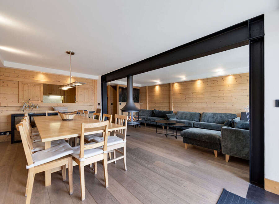 Experience modern mountain living in this stunning open-concept space, featuring a cozy dining area with a natural wood table and chairs, perfect for family gatherings.