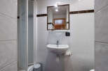 This compact bathroom features a practical shower enclosure and a clean white sink with a chrome faucet.