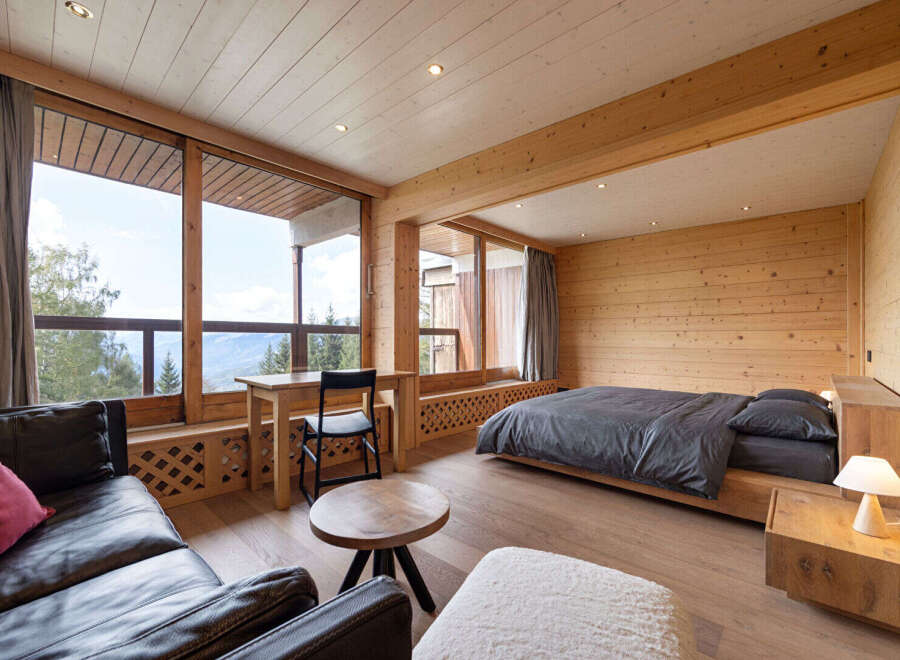 Experience breathtaking mountain views from this beautifully appointed bedroom, featuring a cozy seating area and a comfortable bed.