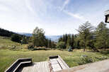 Enjoy breathtaking mountain views from this stunning property's expansive wooden deck, perfect for outdoor dining and relaxation.
