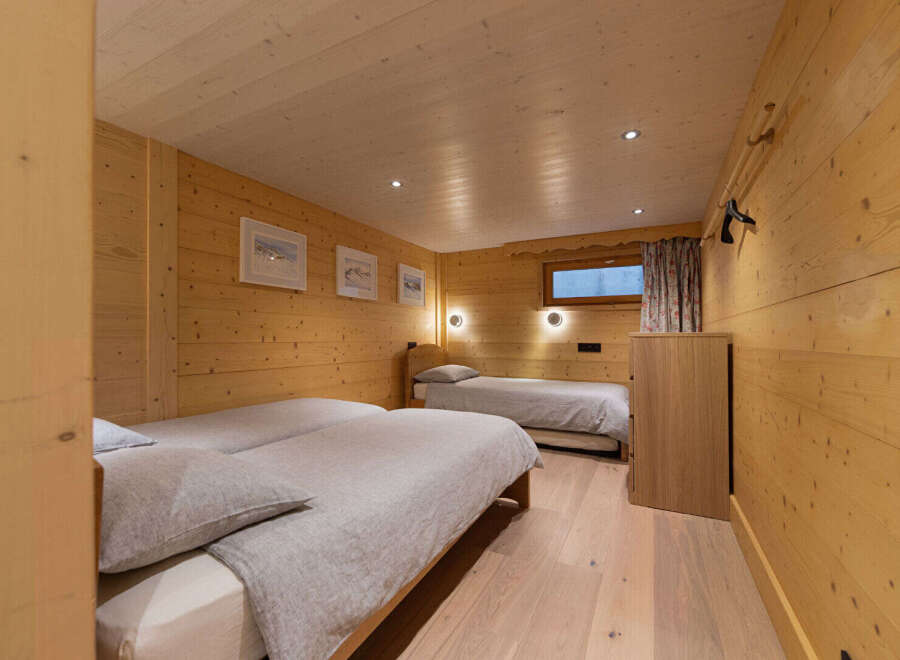 Experience cozy mountain living in this charming wooden bedroom, featuring two comfortable beds perfect for families or groups.