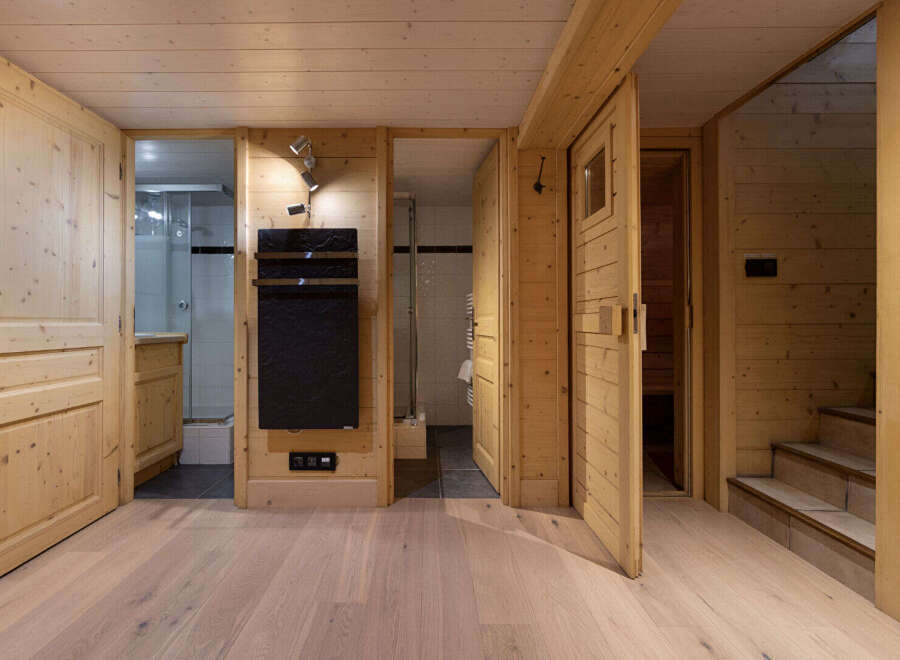 Step into a luxurious wooden cabin featuring a modern bathroom with a sleek black towel warmer and a glass-enclosed shower.