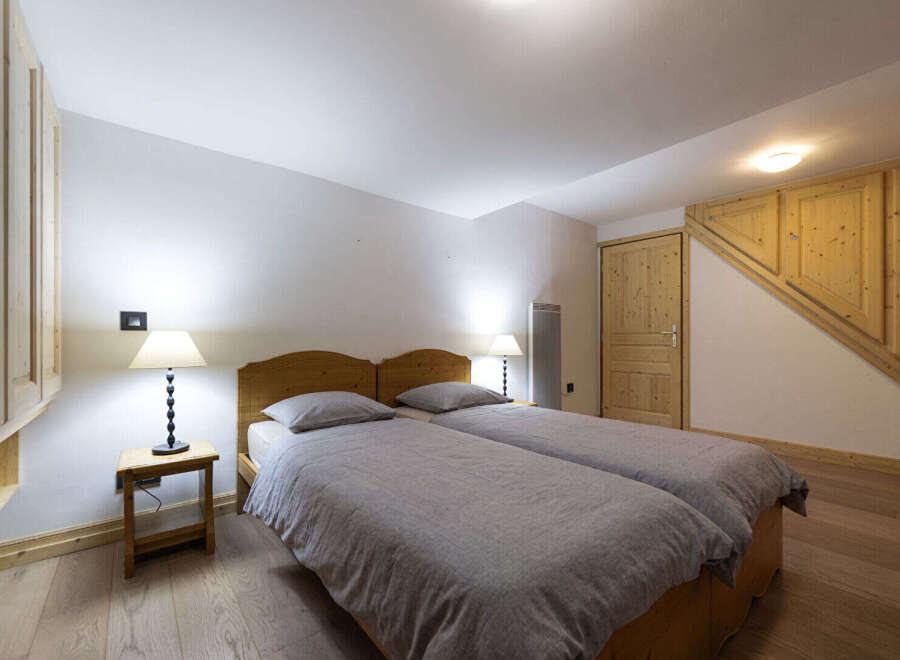 This charming bedroom features two comfortable twin beds with plush grey linens and wooden headboards.