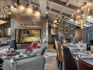Experience luxury living in this stunning mountain retreat, featuring a spacious open-plan living area with a modern fireplace and a large flat-screen TV displaying a dramatic climbing scene.