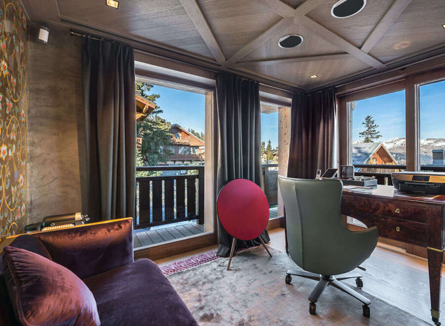 Experience luxury living in this stunning mountain retreat, featuring a sophisticated home office with a rich wood desk and an ergonomic chair.